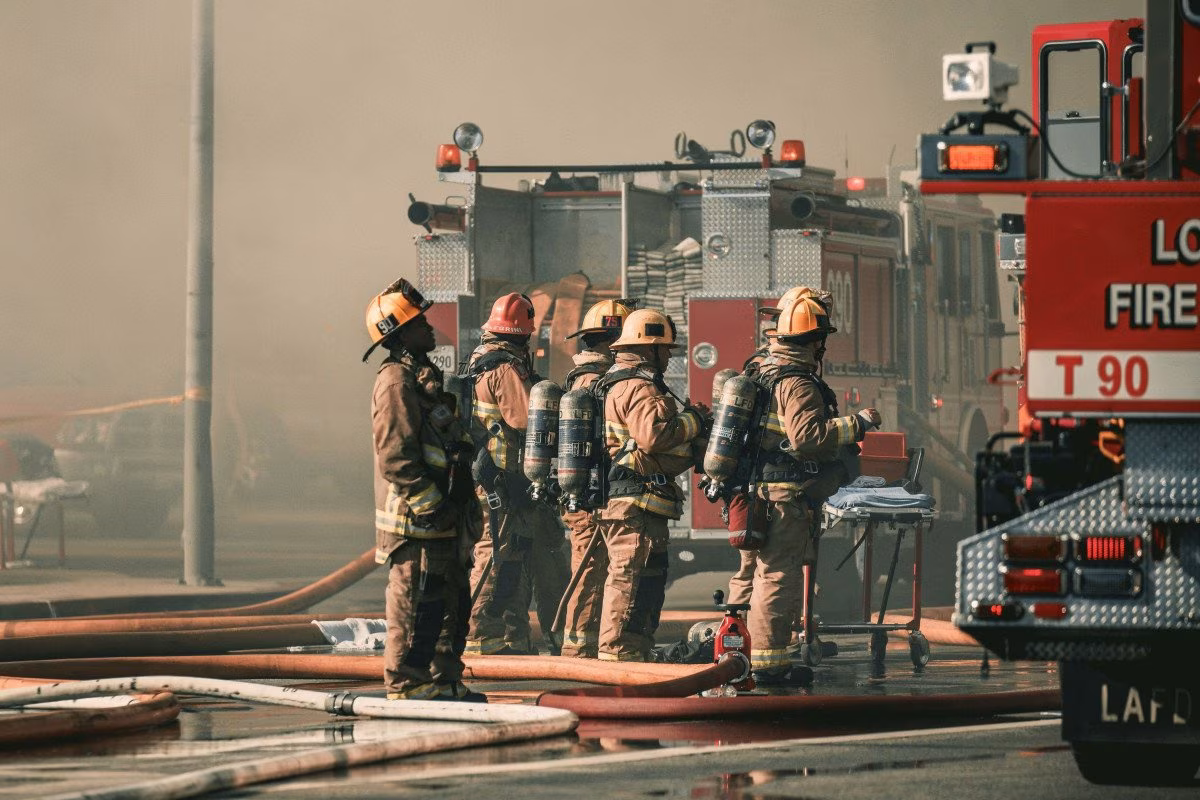 Firefighters in Los Angeles stand by their fire truck, hoses ready. from Stockmark.it