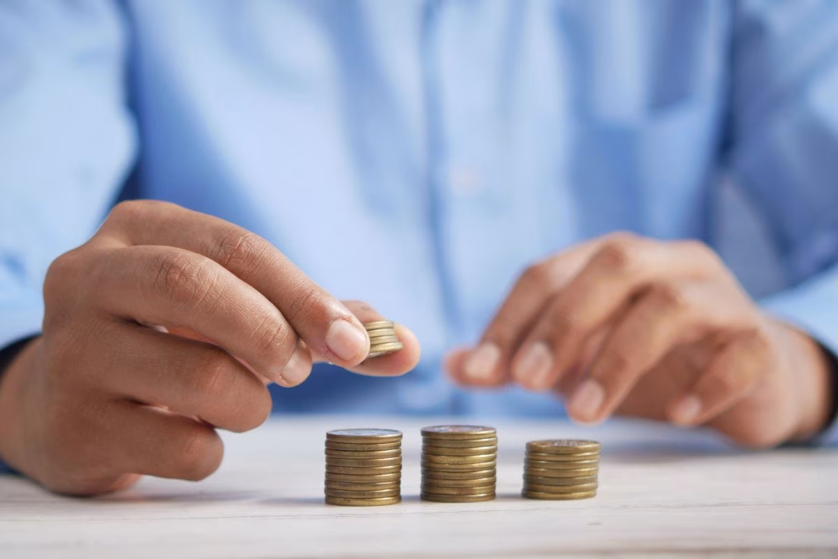 Person stacking coins, symbolizing UK pension funds and tech growth challenges. from Stockmark.it