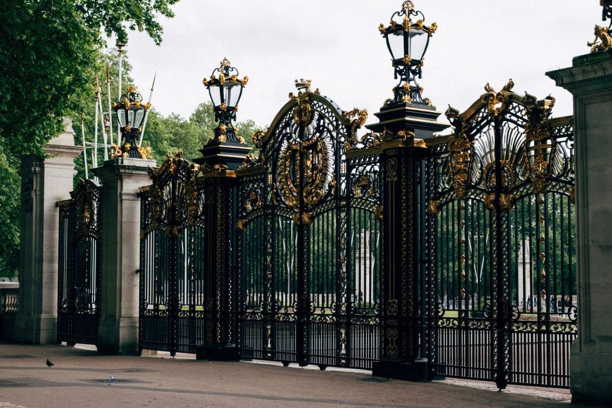 Ornate black and gold gates, possibly Buckingham Palace, with trees behind. from Stockmark.it