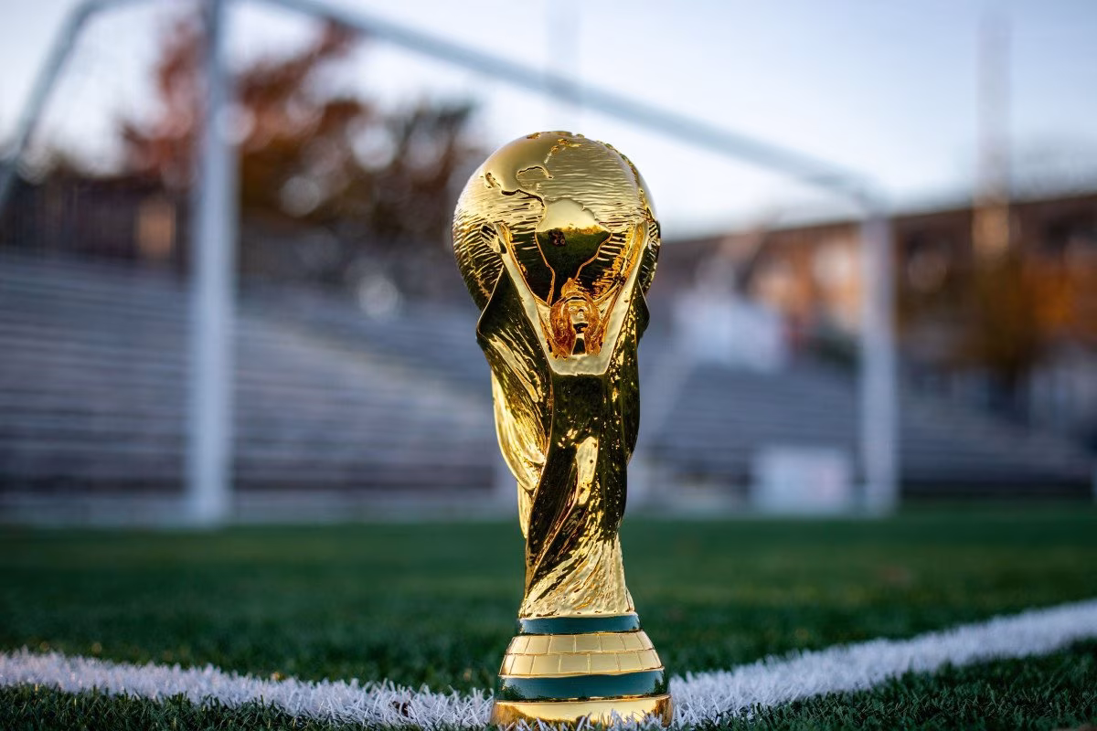 Golden World Cup trophy on a soccer field, representing sports media victory. from Stockmark.it