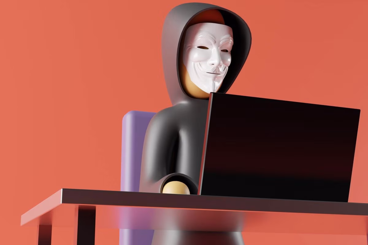 Anonymous hacker in Guy Fawkes mask using a laptop at a desk from Stockmark.it