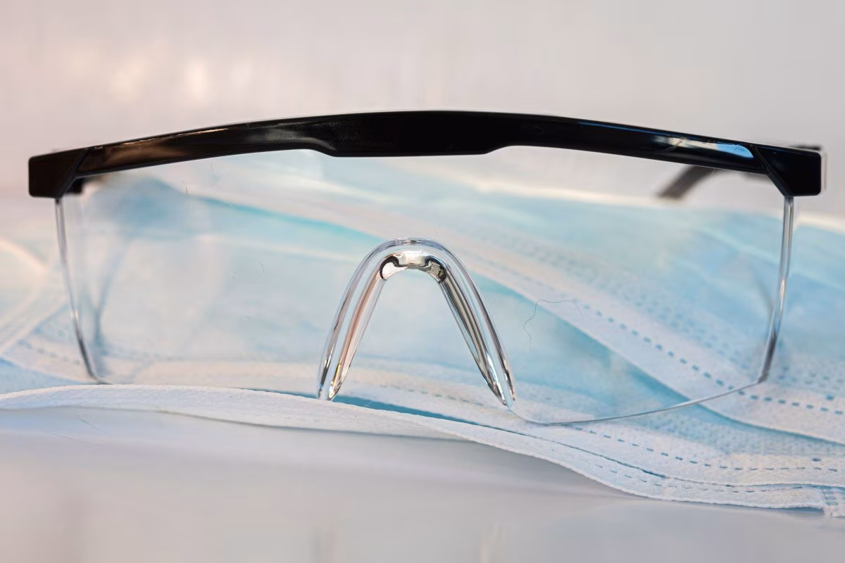 Protective glasses and face masks, symbolizing costly COVID-19 PPE failures. from Stockmark.it
