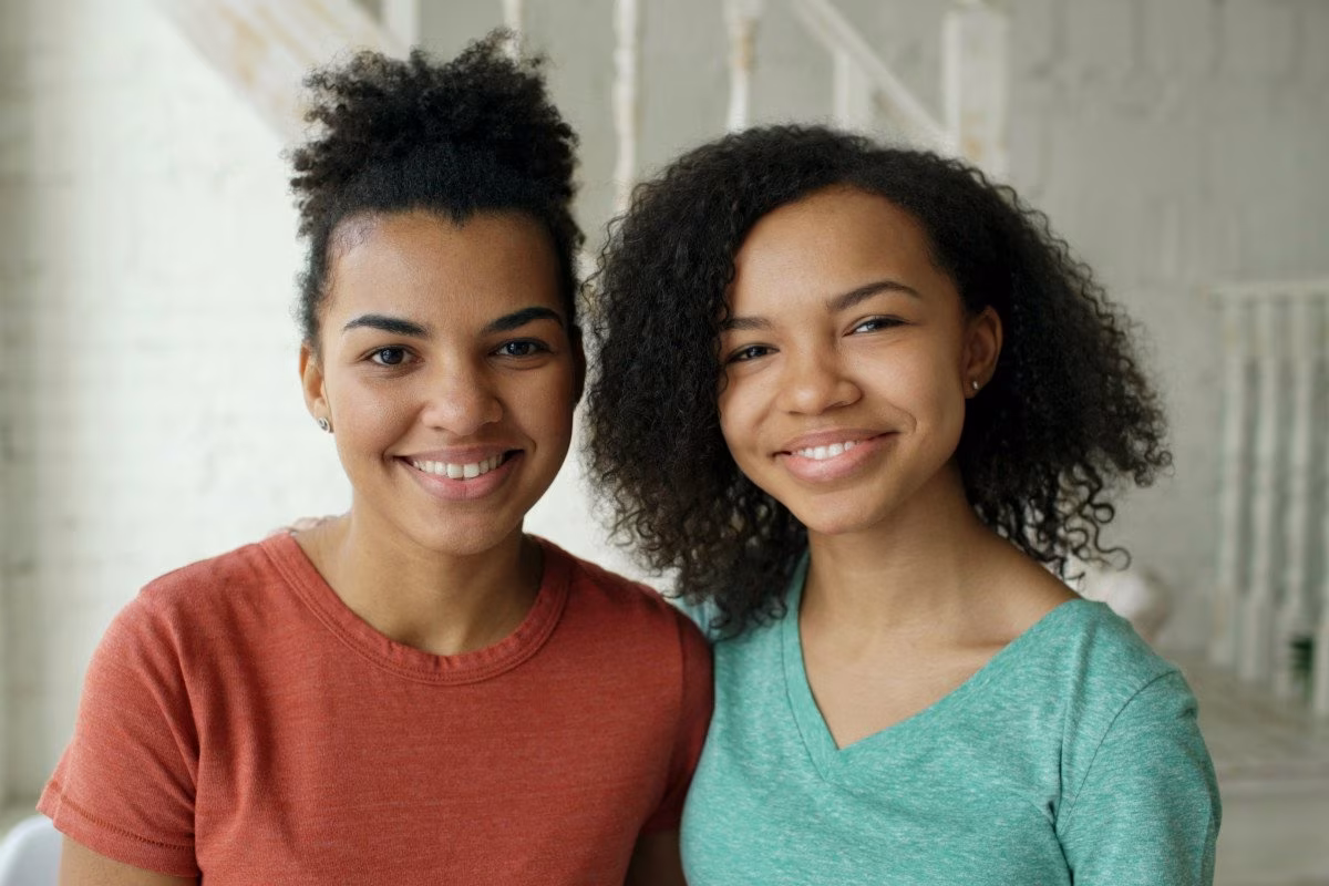 Two young women smiling, representing adult children living at home. from Stockmark.it